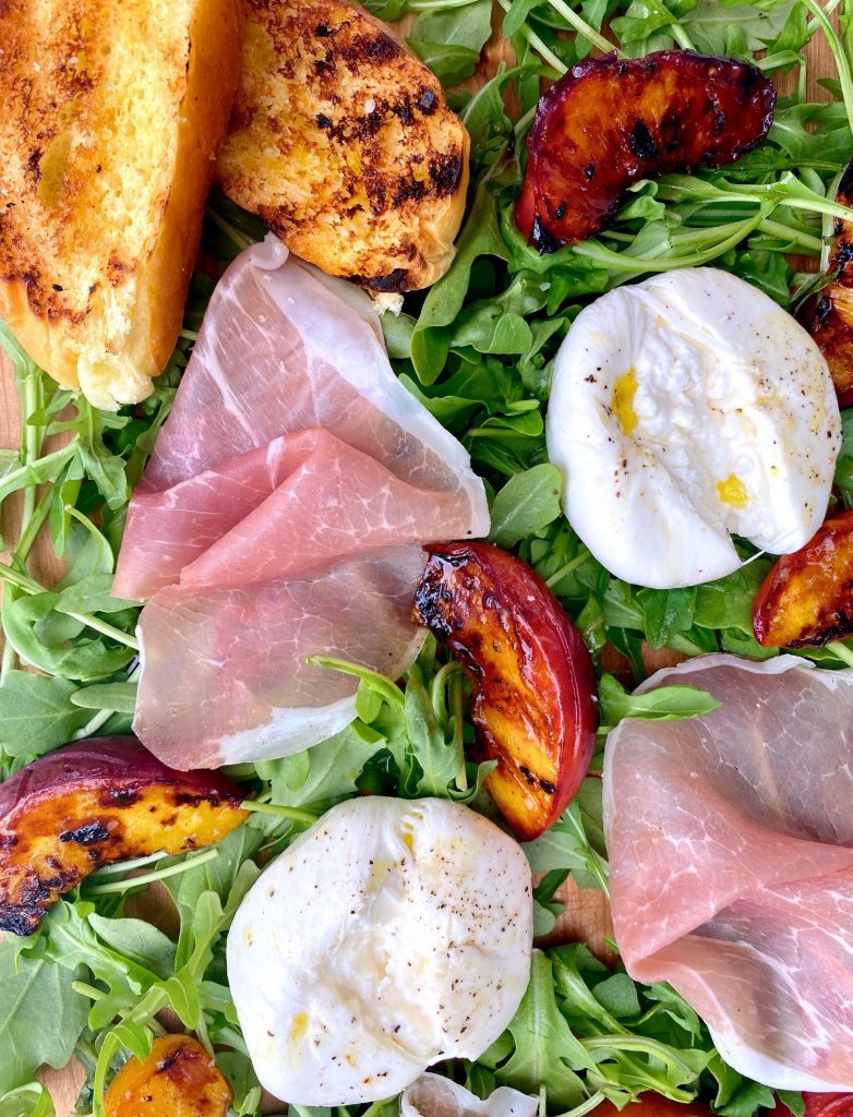 Grilled Peaches with Burrata & Prosciutto on a bed of baby arugula